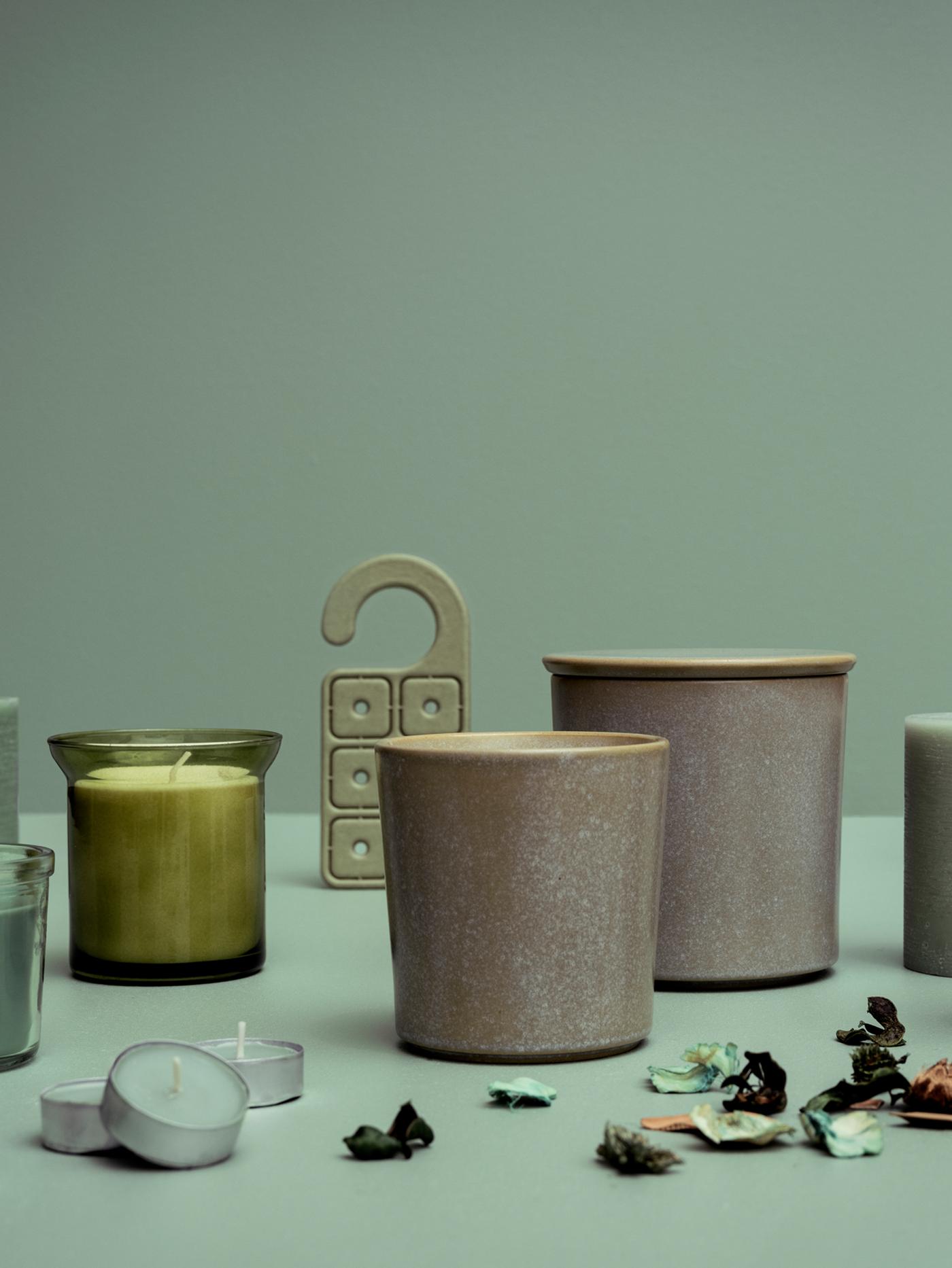 A display of several HEDERSAM fresh grass scented candles, potpourri and a scented hanger against a green background.