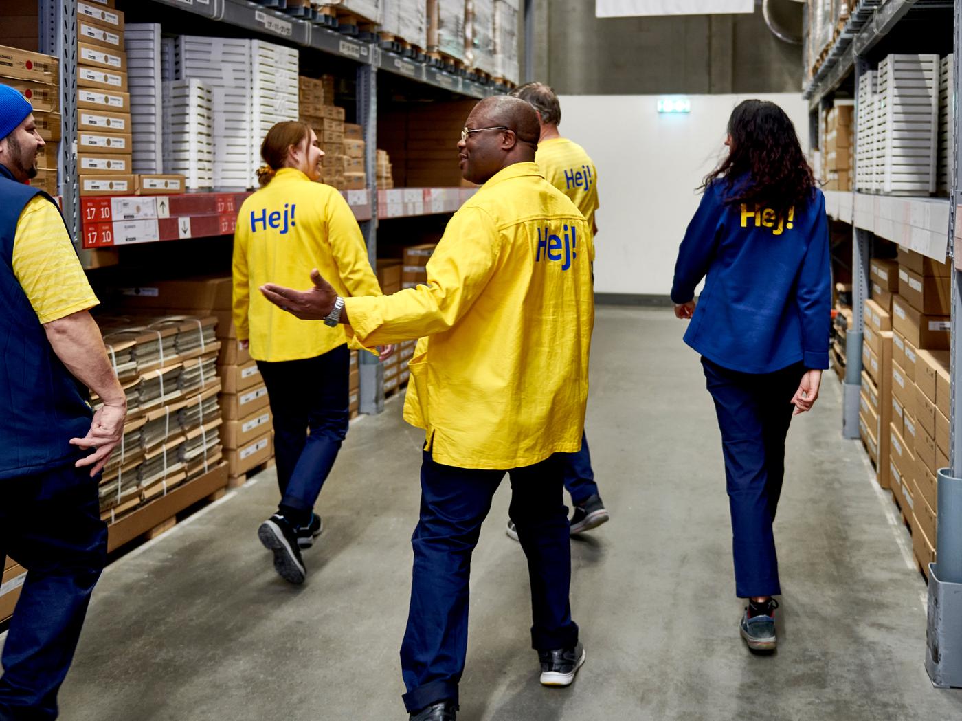 A diverse group of IKEA co-workers walking through the self service department of an IKEA store.
