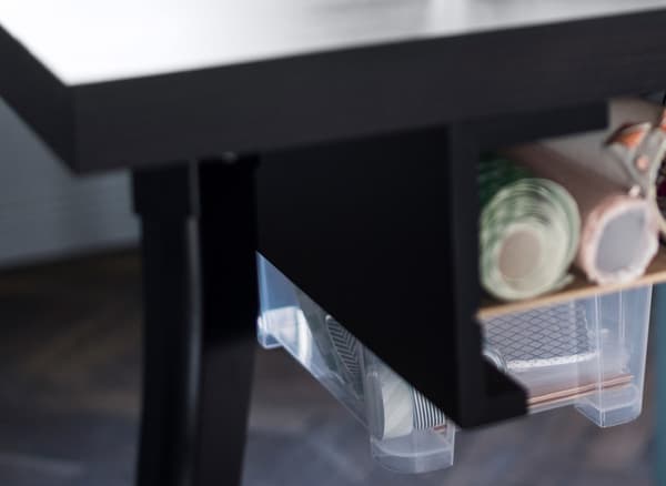 A DIY desk drawer made with two picture ledges attached under a table and clear plastic boxes as sliding drawers.