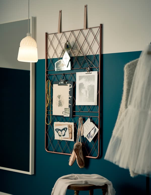 A DIY metal wire inspiration board hanging by leather straps on a wall.