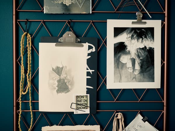  A DIY metal wire inspiration board hanging by leather straps on a blue/green wall.