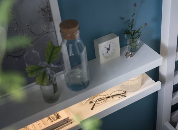 A DIY nightstand made from two MOSSLANDA picture ledges stacked on each other like an open mouth with an LED strip inside