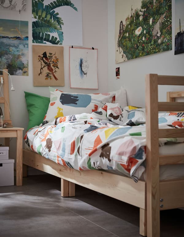 A DOFTKLINT quilt cover and pillowcases on a wooden bed in a student’s dorm room.