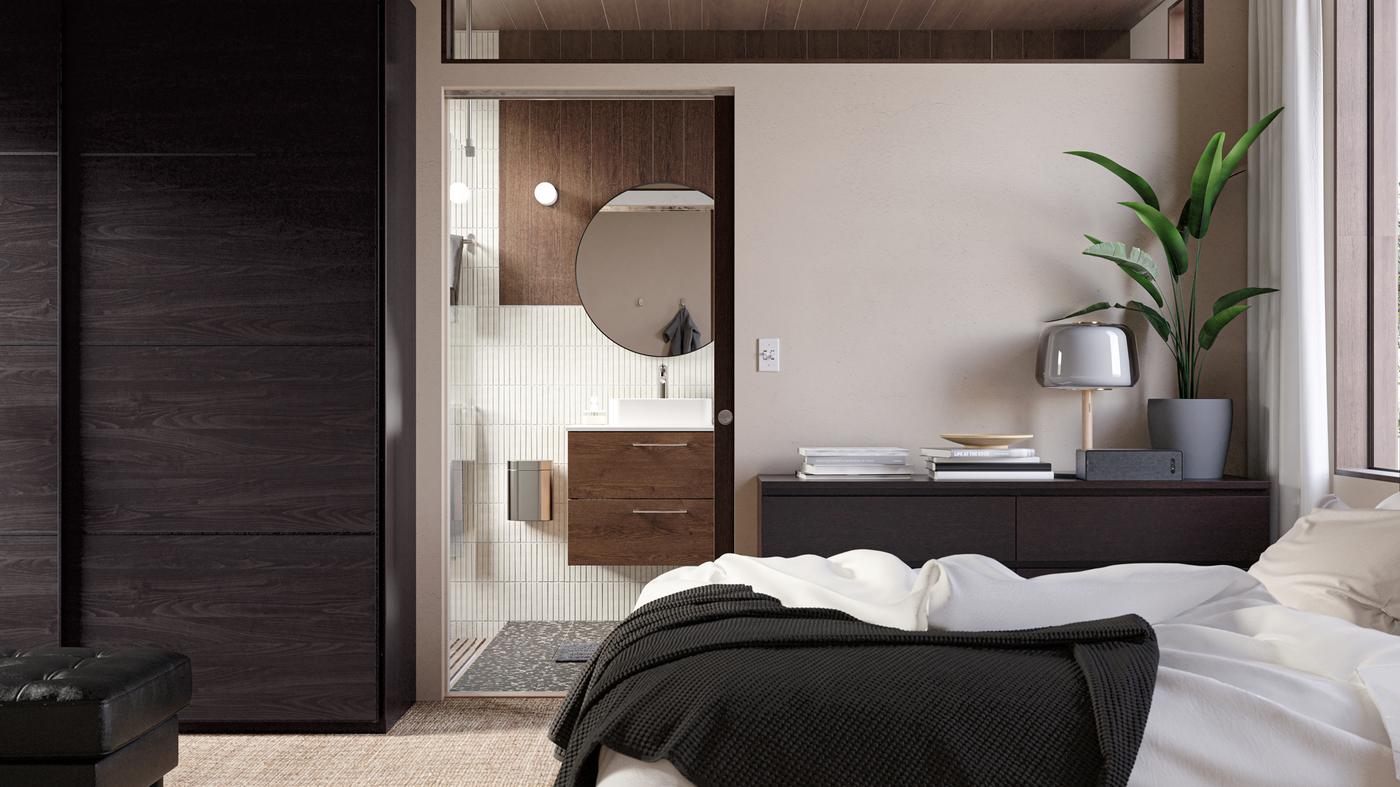 A door in the bedroom offers a peek into a stylish bathroom with a wooden washstand, a round mirror and beige tiles.