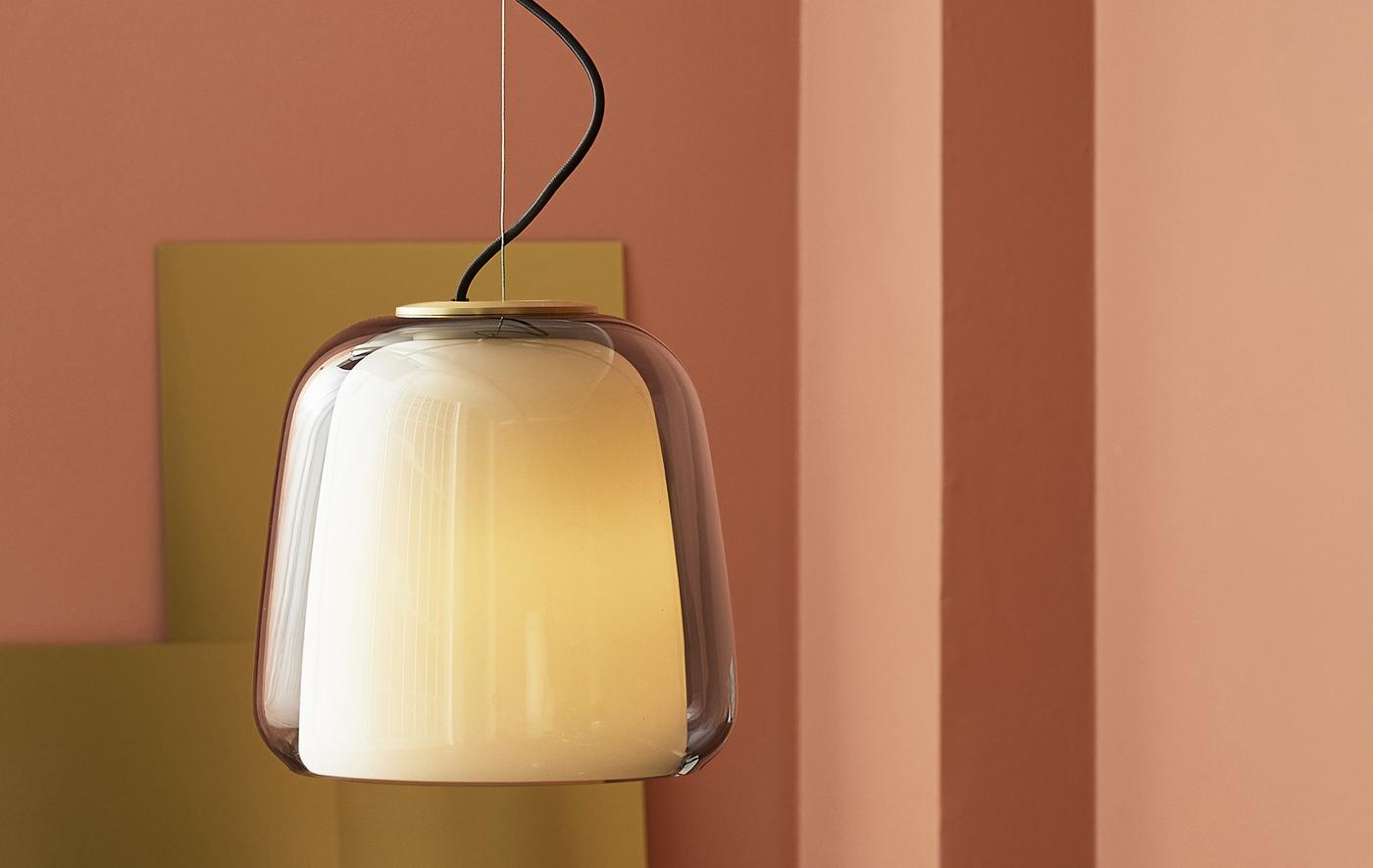A double-layered glass pendant lamp with brass detail in a pink room.