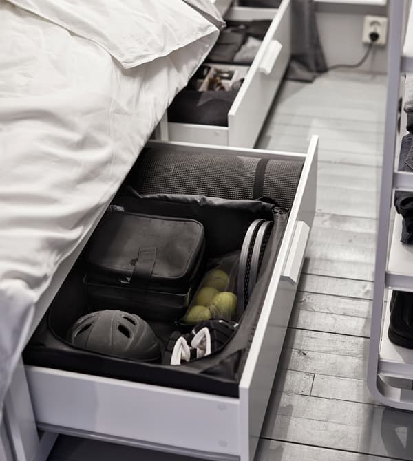 A drawer under the bed has sports equipment kept tidy with interior organisers.