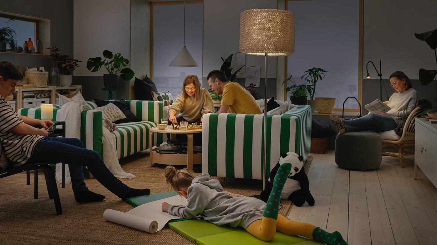 A family spend time together at home. NÄVLINGE pendant lamp, ISBRYTARE table lamp and NÄVLINGE floor lamp brighten the room.