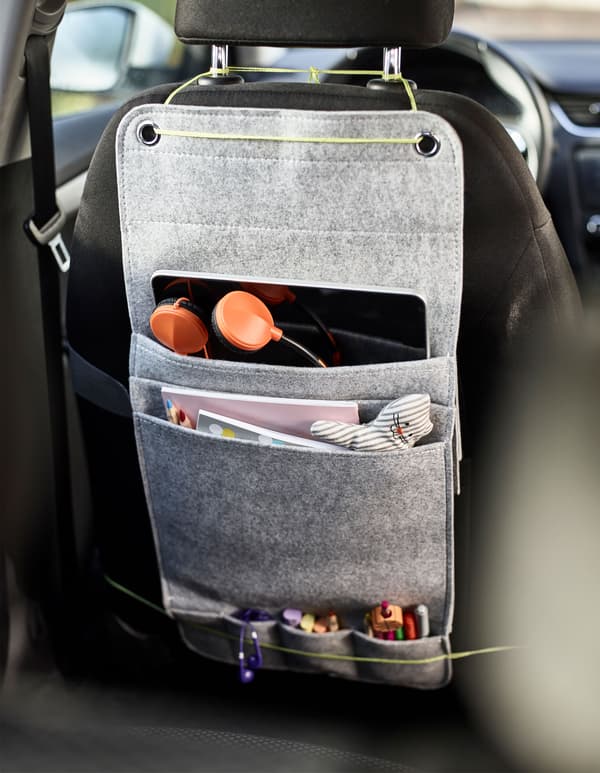 A felt hanging organiser tied to the back of a car seat with space for markers, coloring books and a tablet for kids as a diy car organiser.