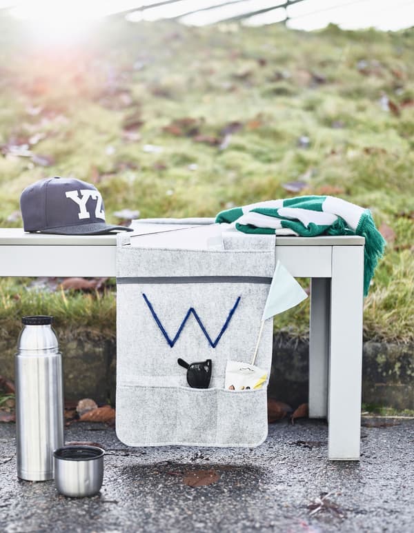 A felt hanging organiser with pockets of snacks, sunglasses and sports flags secured to an outdoor bench as a diy stadium cushion.