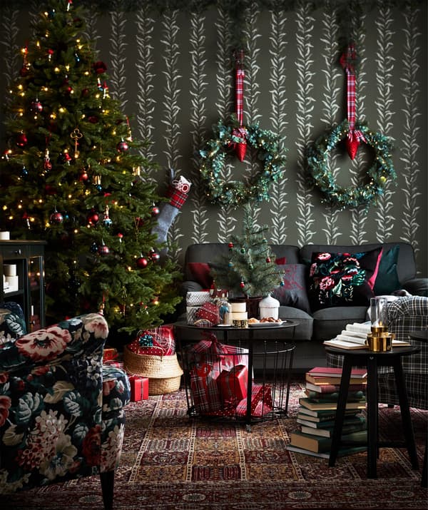 A festively decorated living room with trees and garlands and an IKEA GUALÖV storage table placed in front of the sofa.