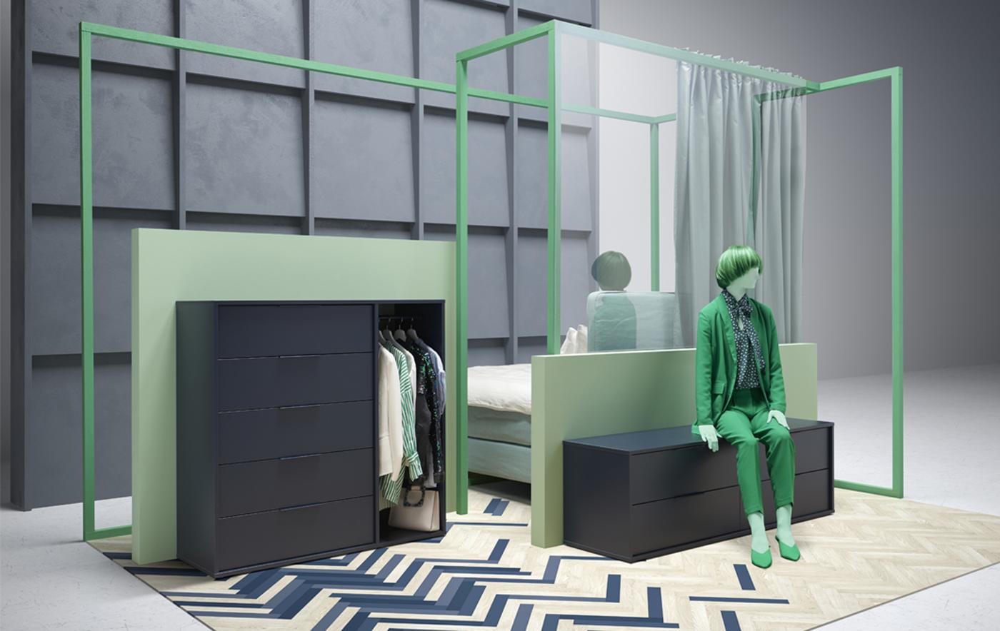 A figure dressed in green sits on a low chest, next to a taller chest with drawers and clothes hanging up.