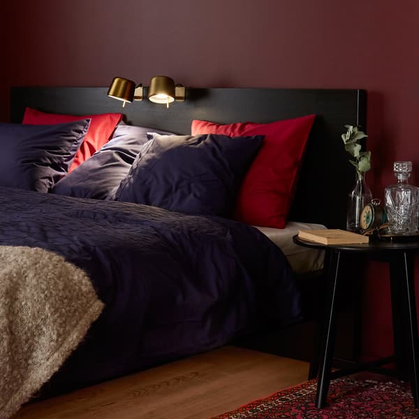 A floor lamp lights an armchair reading space, while a curtain functions as a room divider.