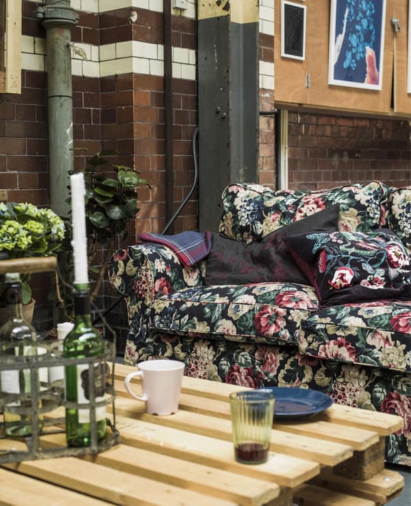 A floral sofa and pallet table in an industrial space.