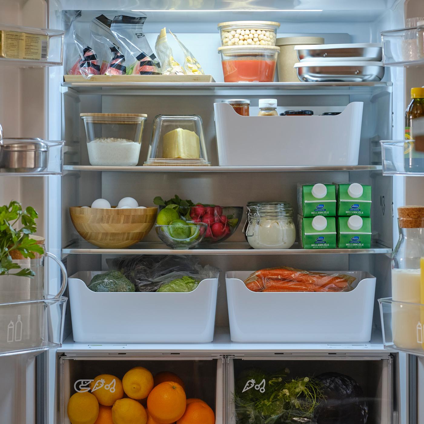 A French door fridge/freezer with both doors open showing foods in containers, boxes, jars, resealable bags and a carafe.