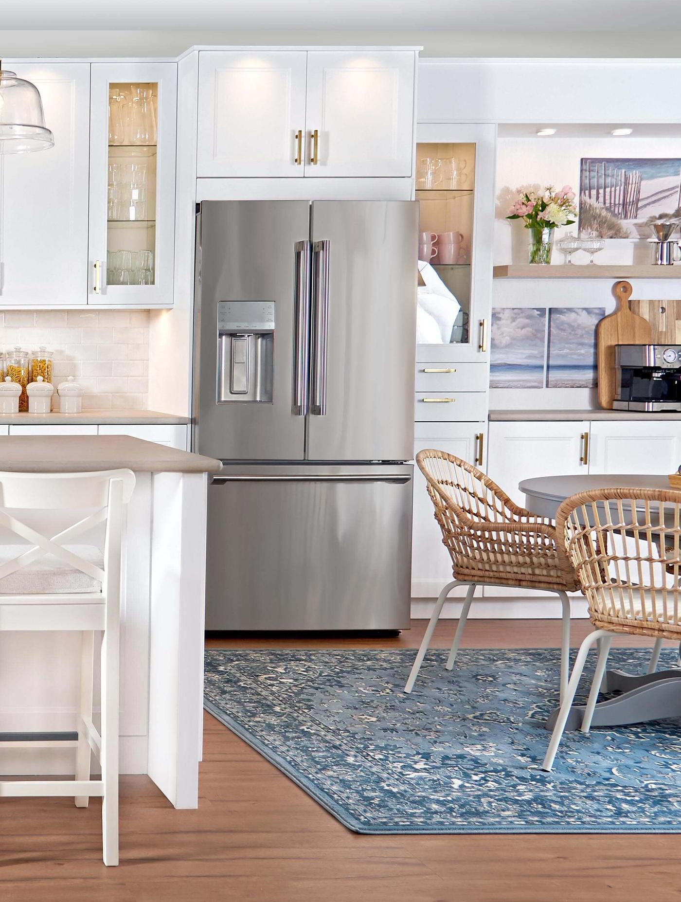 A fridge/freezer with matte white AXSTAD fronts are placed just outside a small kitchen with a black RÅSKOG trolley.