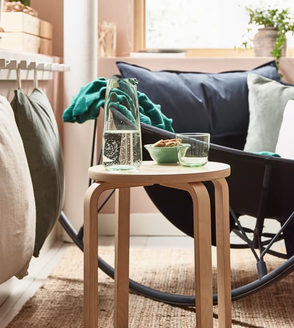 A FROSTA wood stool being used as a side table in a cosy living room.
