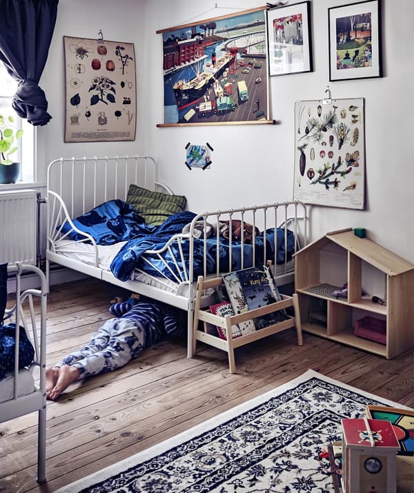 A fun children’s bedroom with white walls, book storage, a dolls house and plenty of wall art.