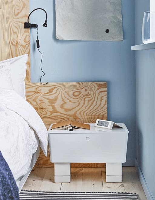 A GIF of a nightstand made from a storage box with plant pots as legs. The pots are full of nighttime necessities.
