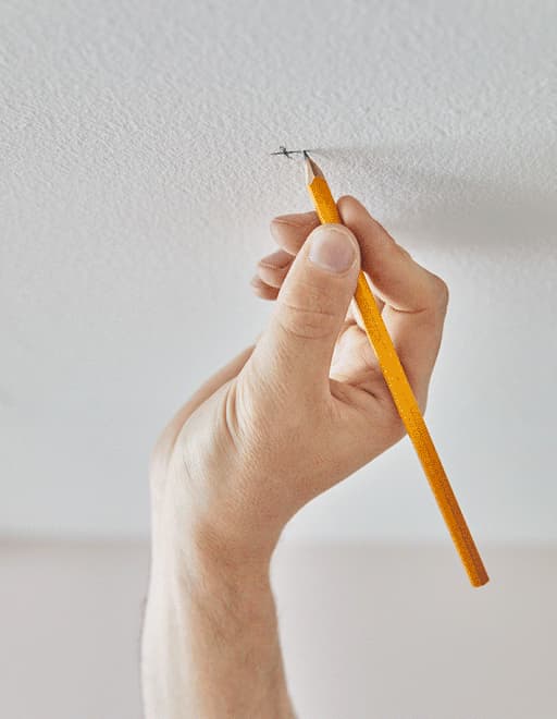 A GIF of someone drilling holes in the ceiling and installing an IKEA VIDGA track system to create bed curtains.
