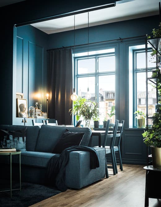 A GIF shows a roller blind hung from the ceiling, that can be pulled down between the sofa and dining table areas.