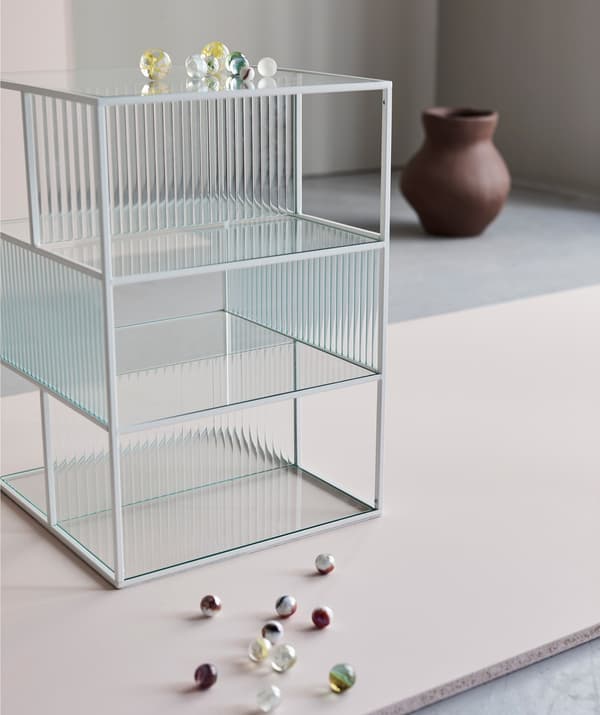 A glass SAMMANHANG display box with a handful of glass beads and an INDUSTRIELL vase.