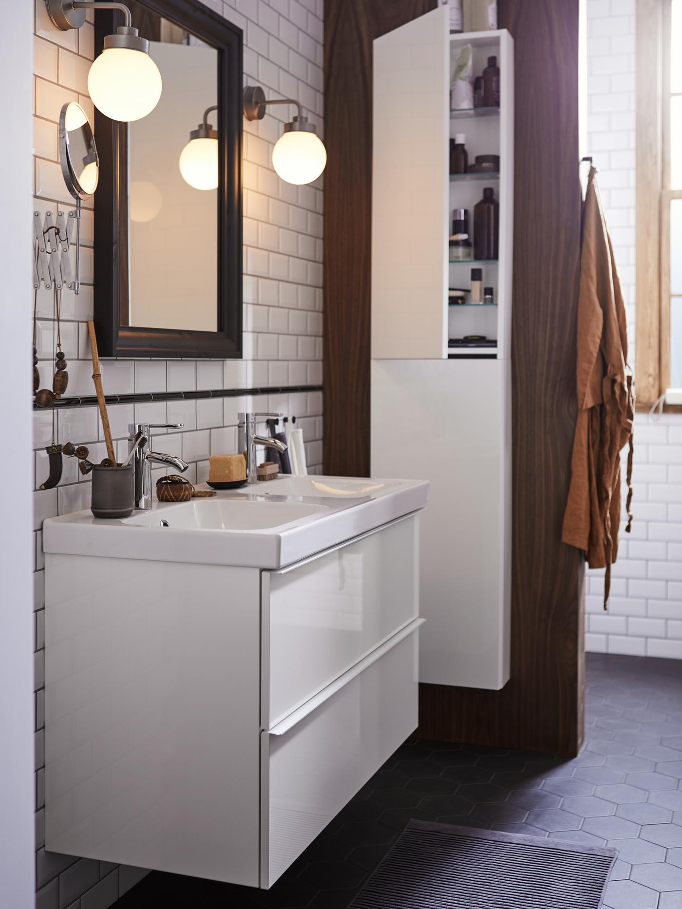 A GODMORGON bathroom with a two drawer wash-stand with a mirror above and an ajar high cabinet to the right, with toiletries.