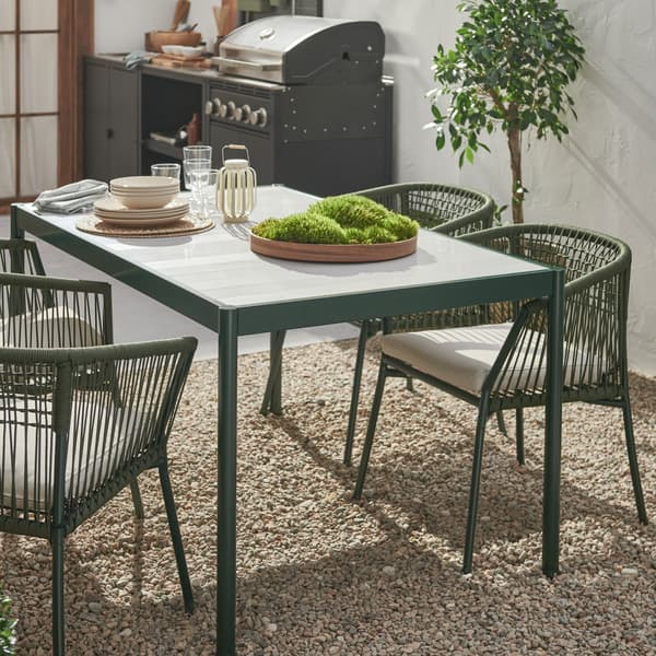 A gravel patio with a dining area formed by dark-green SEGERÖN chairs around a dark-green-and-light-grey SEGERÖN table.