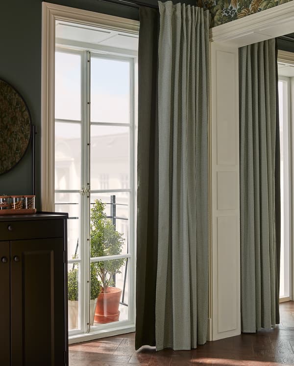 A green block-out curtain and a houndstooth-patterned curtain hang by a balcony door for customised light and privacy.
