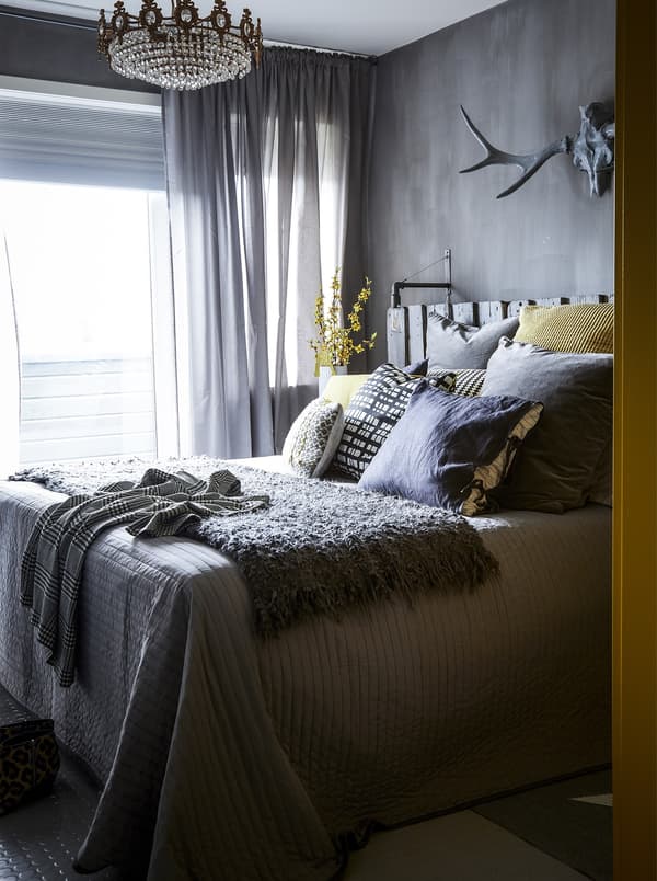 A grey bedroom with yellow flowers and cushions.