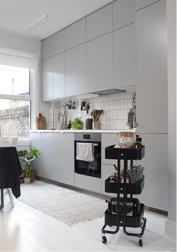 A grey kitchen along one wall with white tile splashback and white worktop.