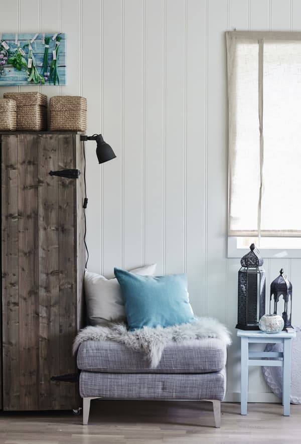 A grey ottoman sofa unit, furnished with a white pillow and bright blue cushion as an accent colour.