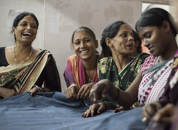 A group of women smiling and working with fabric.