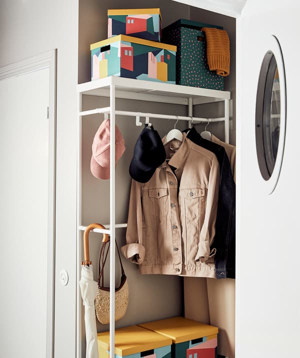A hallway with a MACKAPÄR coat rack. Besides jackets and accessories, the rack is laden with various TJENA boxes.