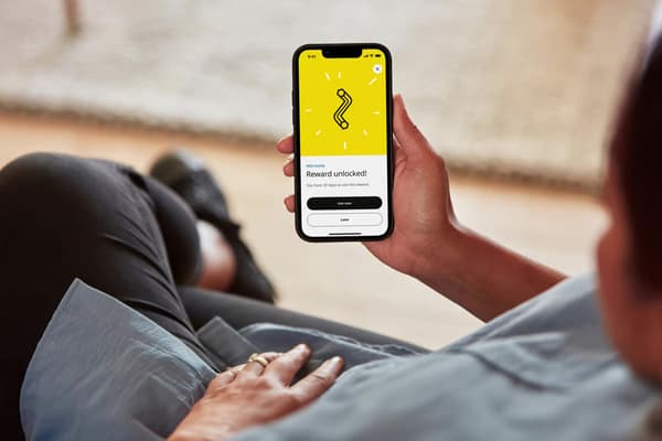 A hand holding a cell phone with a QR code on the screen.