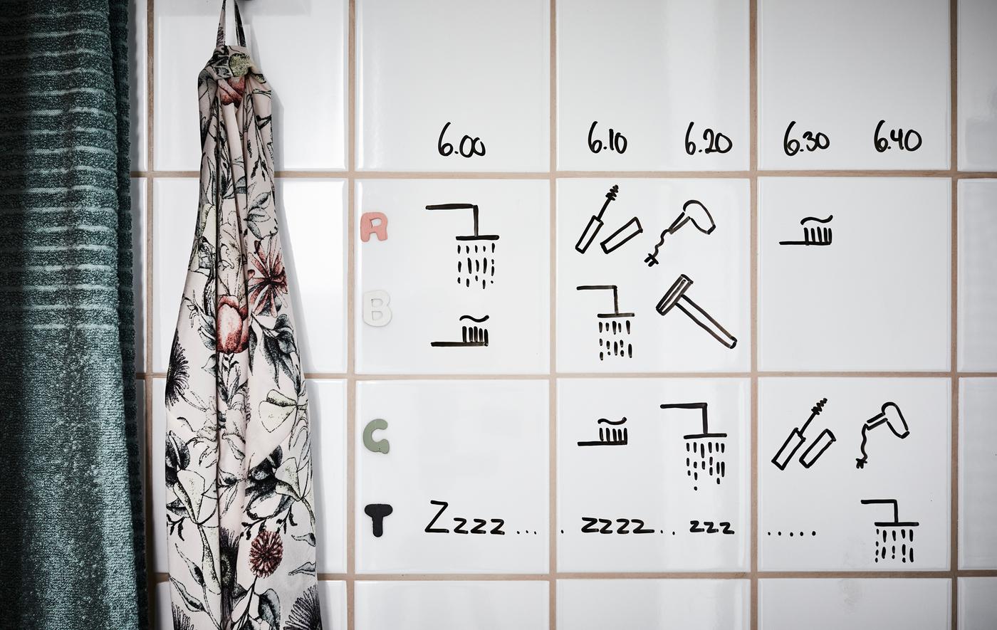 A hand written time schedule made using black marker pen, drawn on white bathroom tiles.