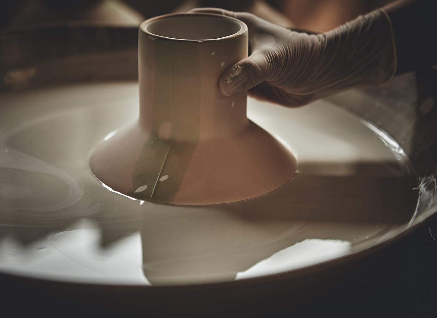 A handmade ceramic vase from the IKEA HANTVERK collection being glazed by hand by immersing it in a bath.