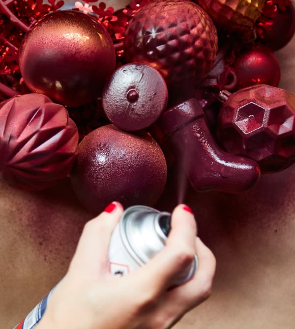 A hanging centrepiece is being spraypainted in a maroon colour.
