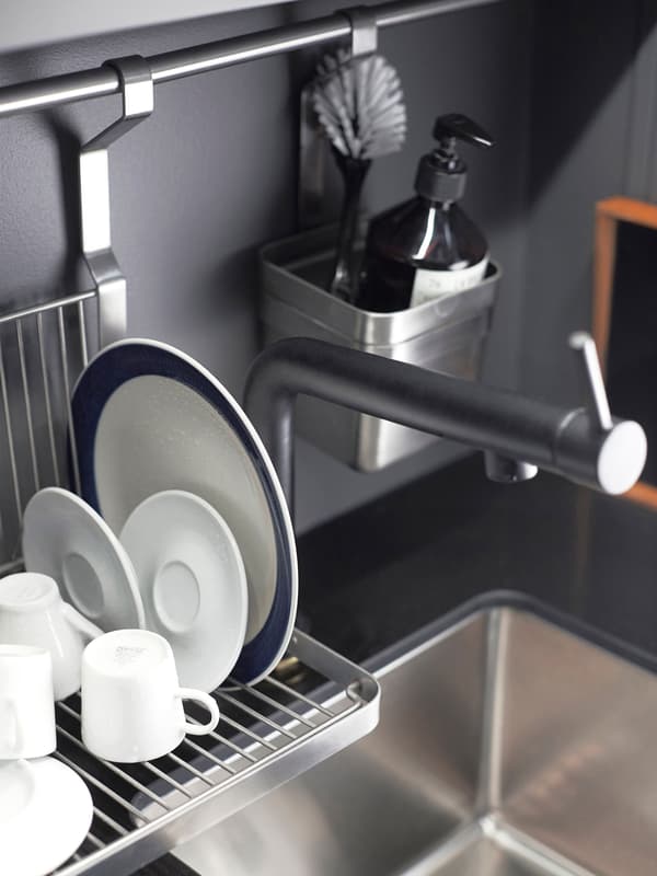  A hanging dish rack dries saucers, mugs and a plate next to the kitchen sink.