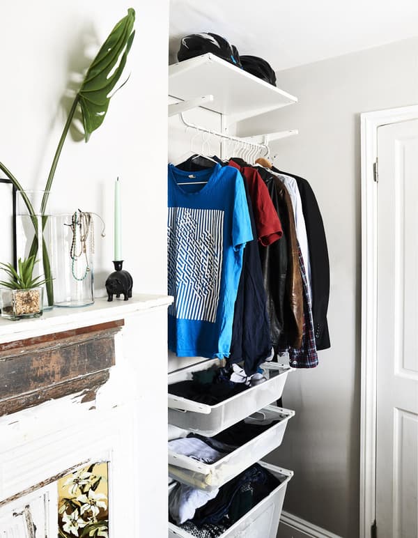 A hanging rail and drawers store clothes in a bedroom alcove.