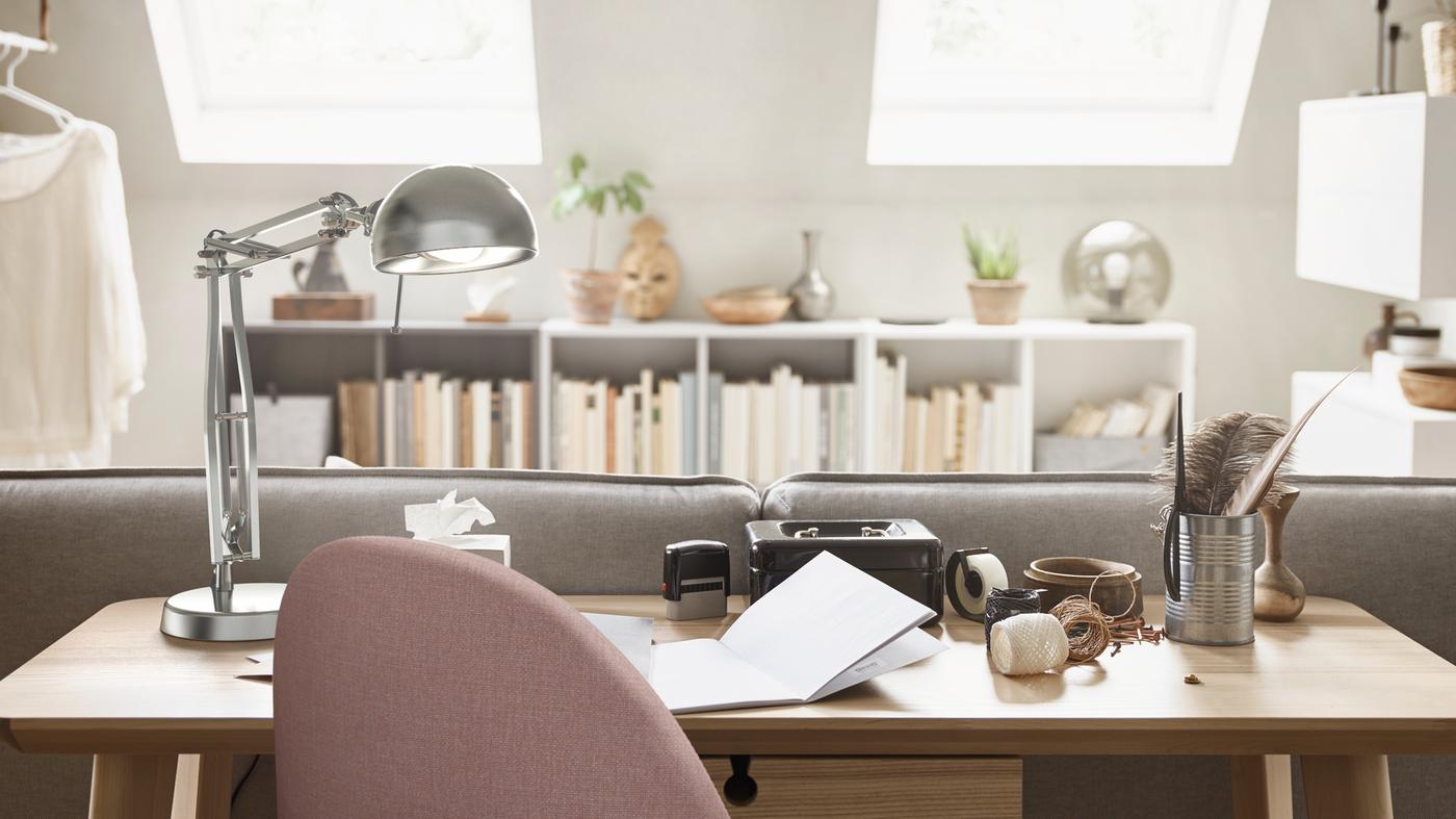 A home office spot with a LISABO desk in ash veneer behind a sofa, a FORSÅ work lamp and a GUNNARED swivel chair.