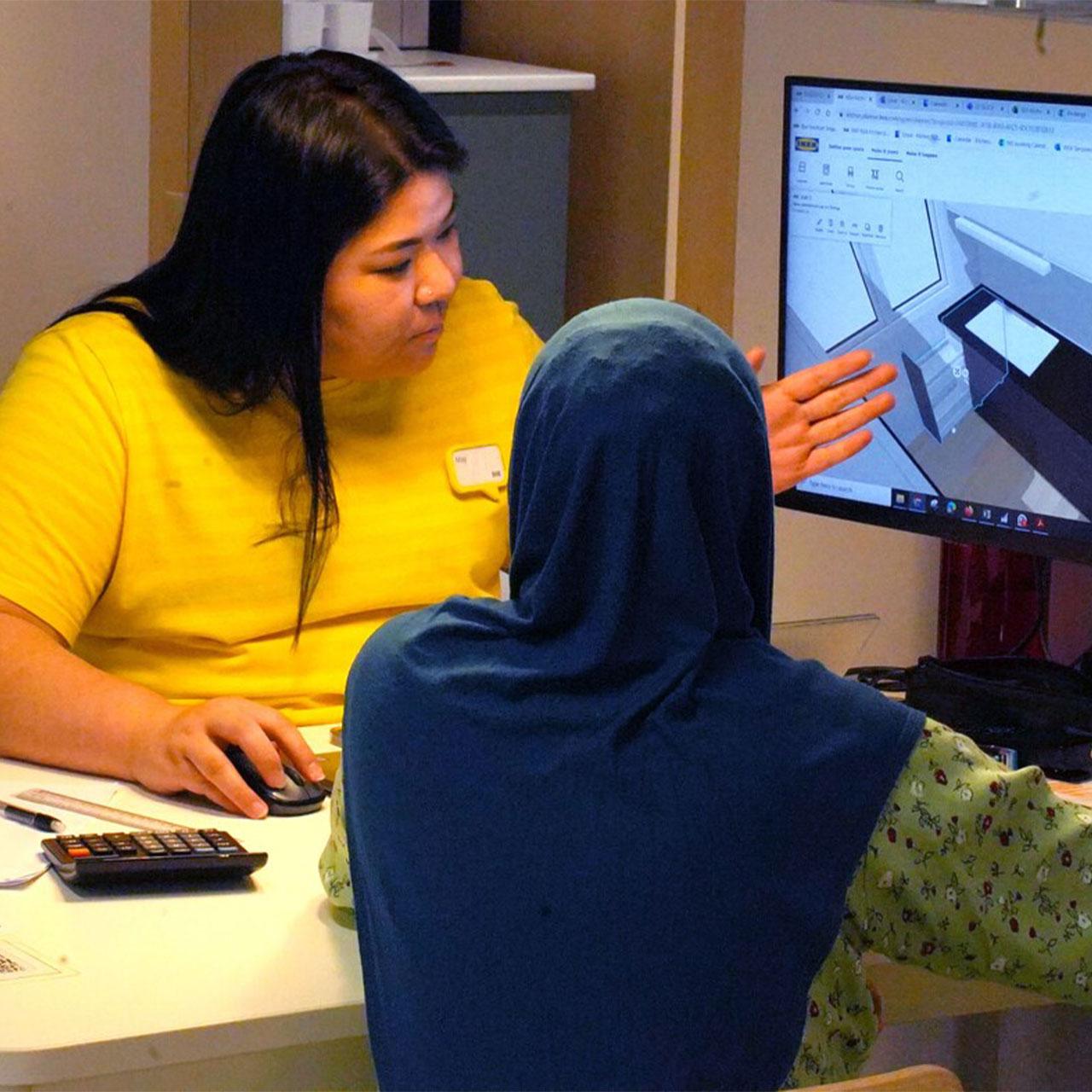 A IKEA kitchen service staff is going through the floor plan with a customer.