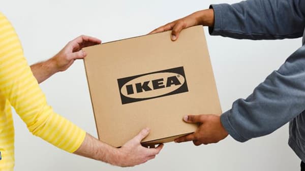A IKEA worker handing an IKEA parcel to a person.