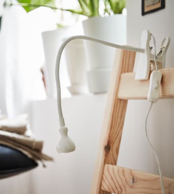  A JANSJÖ LED wall/clamp spotlight clipped onto a chair back.