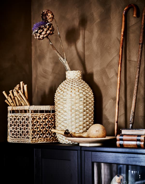 A KAFFEBÖNA decoration vase made from bamboo and deco details in organic materials on top of a dark brown HAVSTA cabinet.