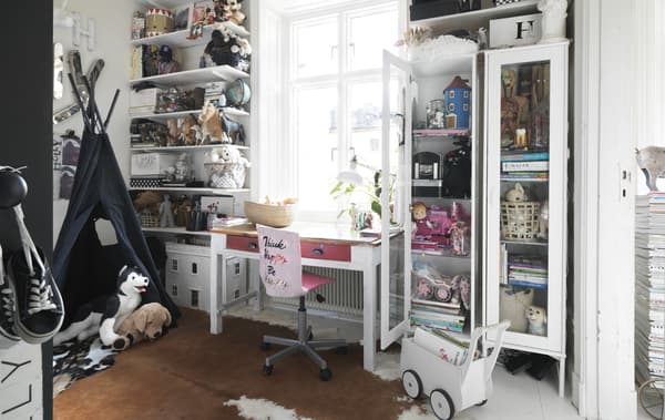 A kid’s bedroom with open storage and pink chair.