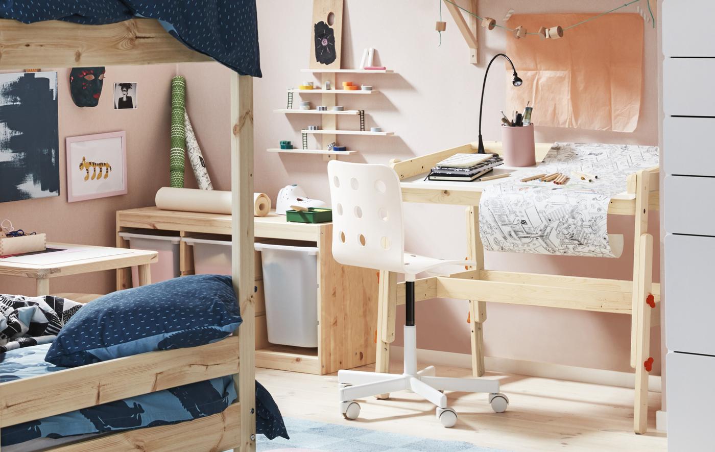 A kid’s room decorated/painted in pale pink with light wooden furniture including a desk and bunk bed.