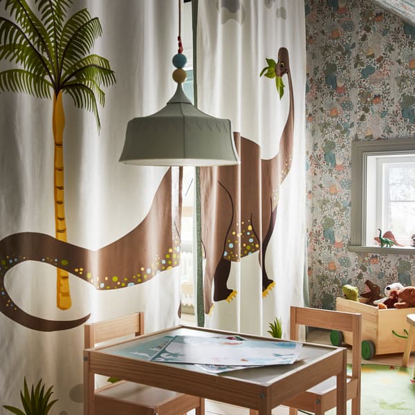 A kid's room with a table and chairs, and scattered toys. The fourth wall is formed by dinosaur-motif curtains drawn shut.
