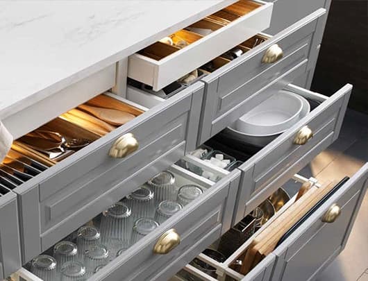 A kitchen cabinet section with open drawers showing glassware, plates and utensils.
