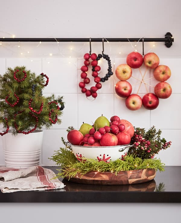 A kitchen counter displays fruits and plant arrangements.
