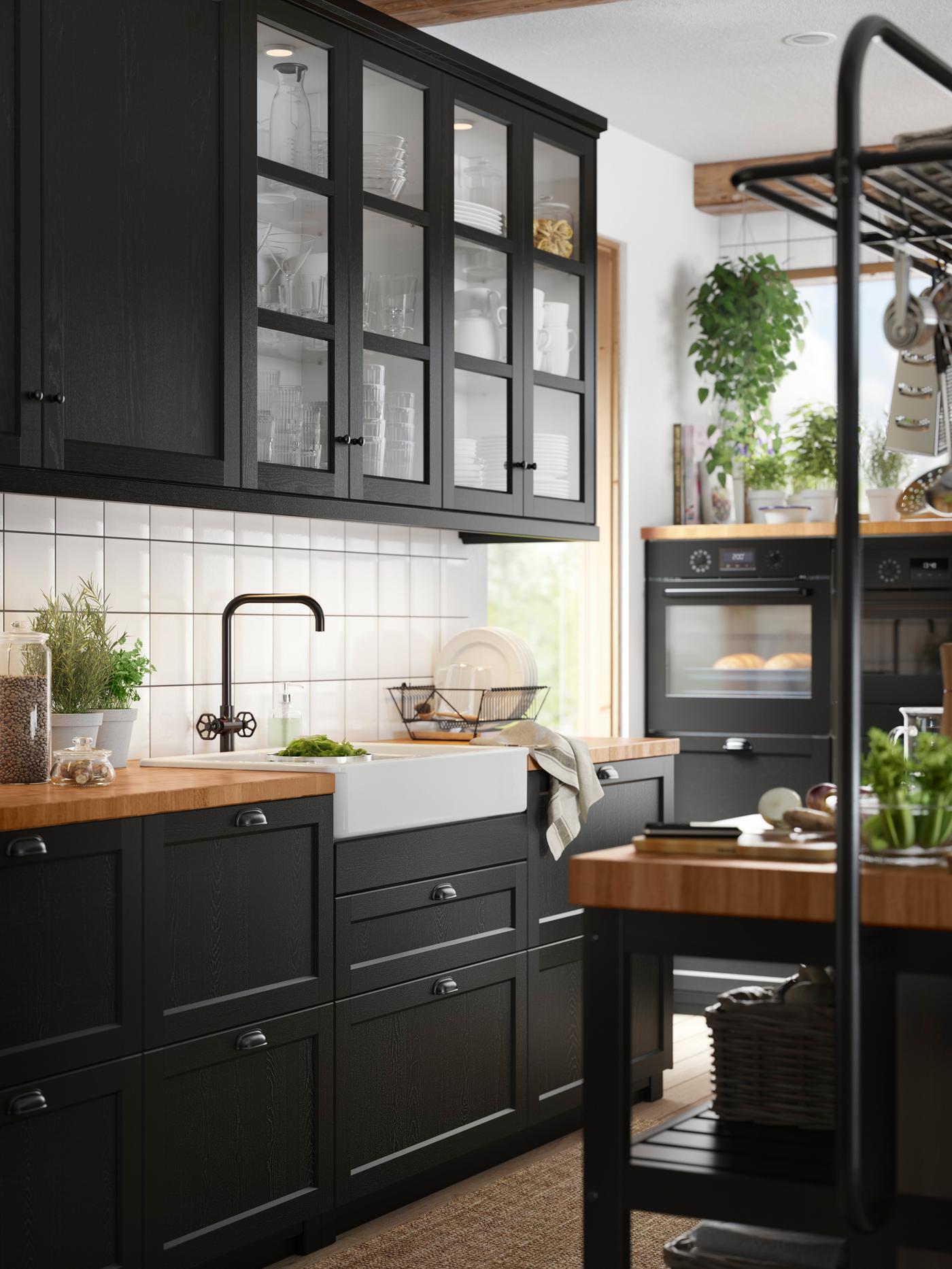 A kitchen featuring glass doors with stained black wood frames, cabinets with stained black fronts, and a wooden worktop.